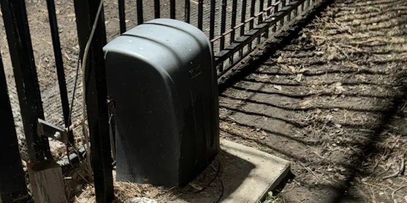 Slide gate operator mounted on its pad at the foot of an iron gate