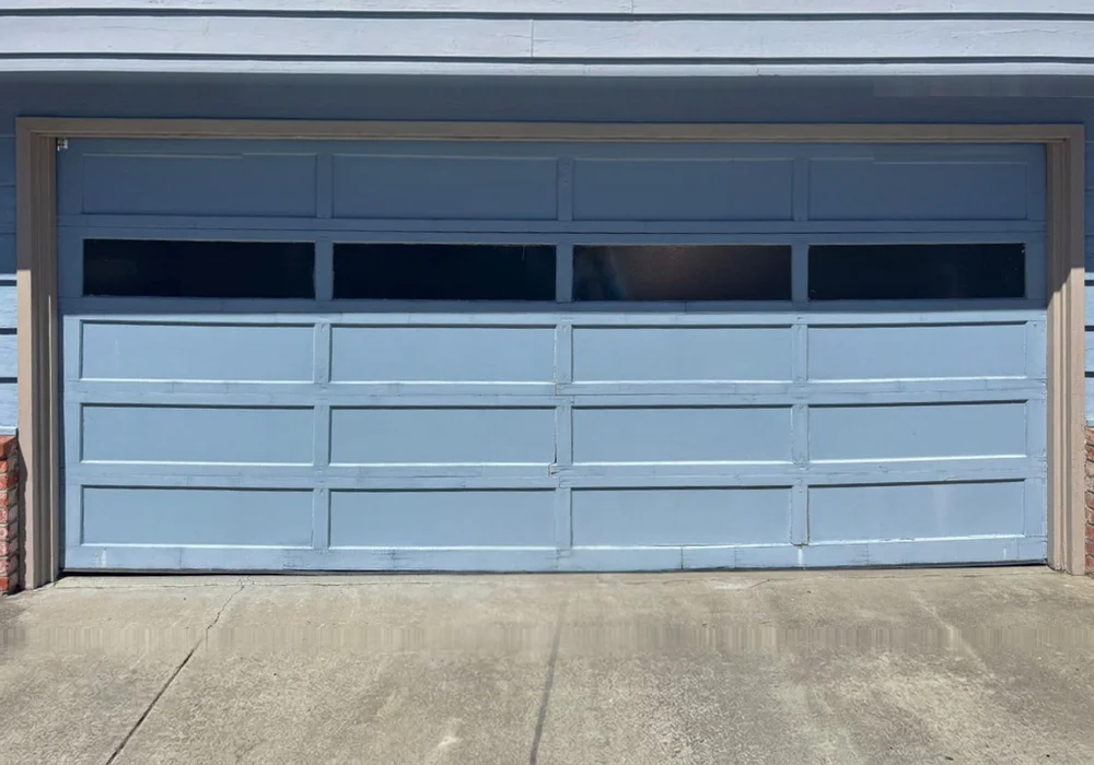Terracotta double garage door stuck part-open, seen from the driveway